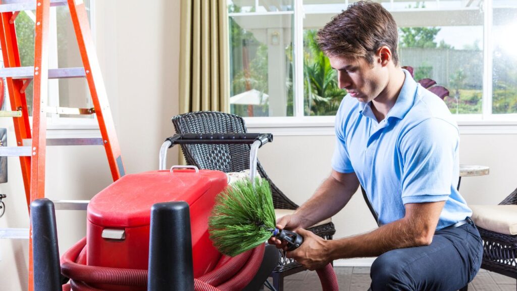 man setting up machine to clean air ducts at home