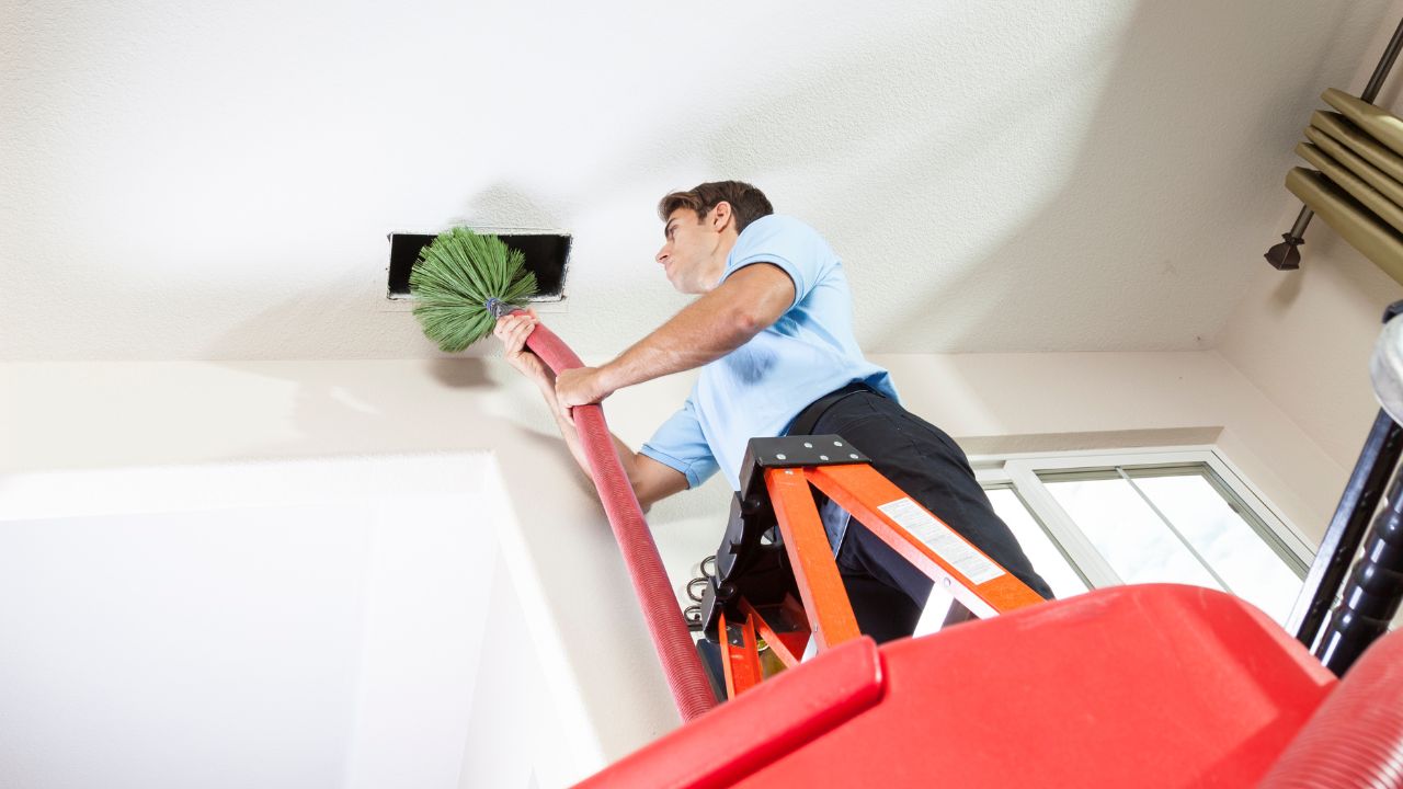 a man contractor using a cleaning brush to clean an air duct
