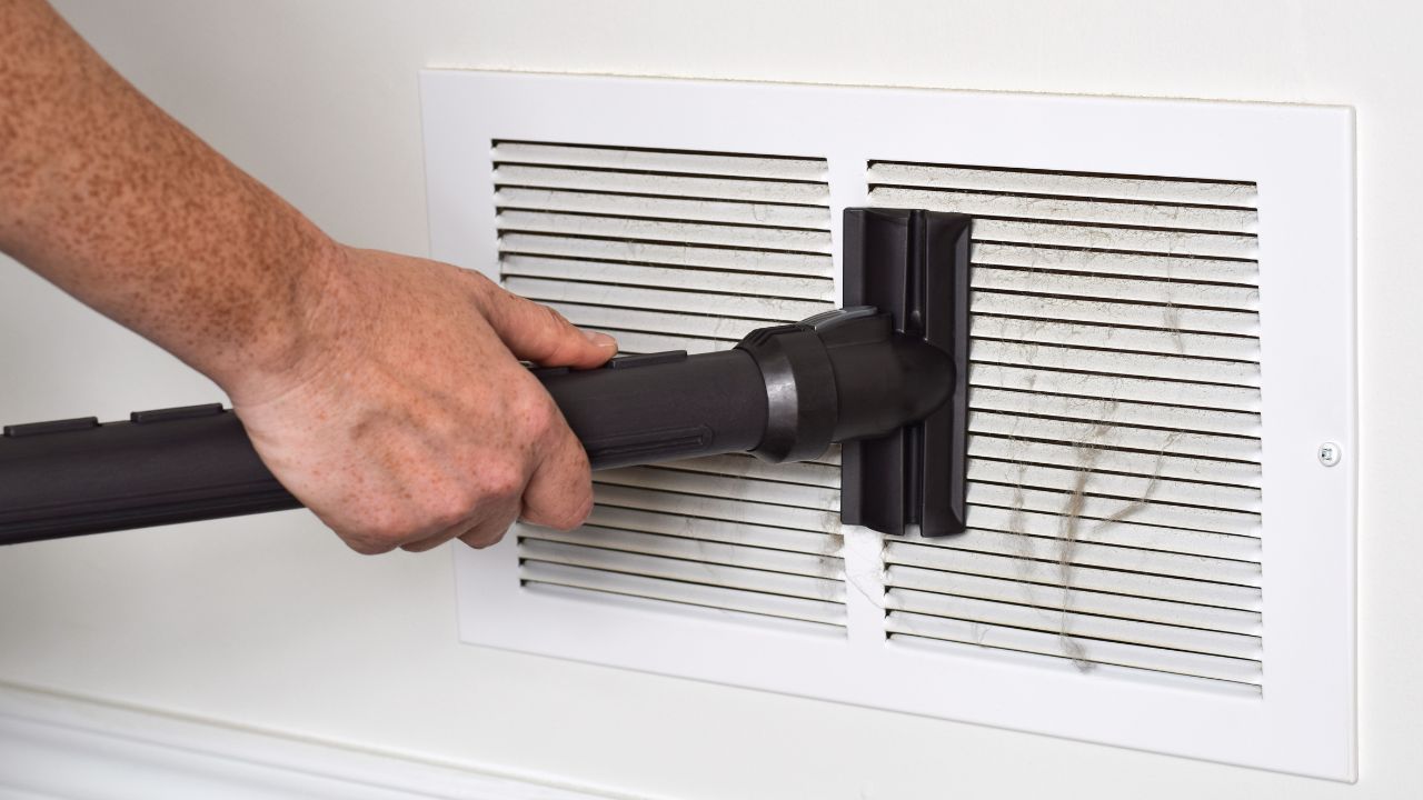 persons hand vacuuming dirty return air vents